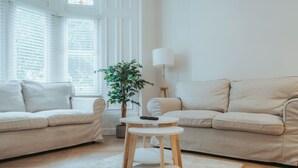 A modern living room with two beige sofas, a small wooden table, a potted plant, and a floor lamp.