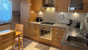 Una cocina moderna con armarios de madera, horno empotrado, un lavamanos y una ventana con cortinas.