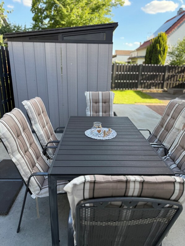 A patio with a dark wooden table and striped cushioned chairs.