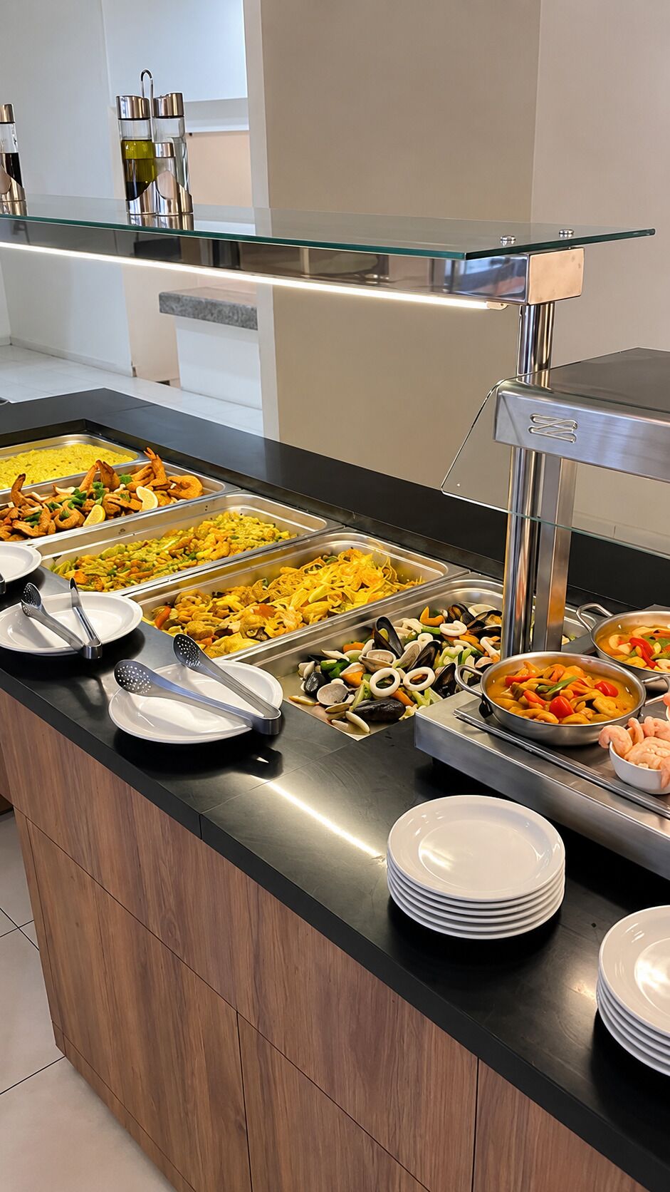 A buffet setup with various food items and serving utensils.