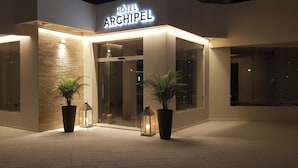 Exterior del Hotel Archipel, con un diseño moderno, que presenta grandes ventanales y plantas en macetas en la entrada.
