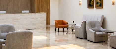 A spacious lobby with a reception desk, seating area, and artwork on the walls.