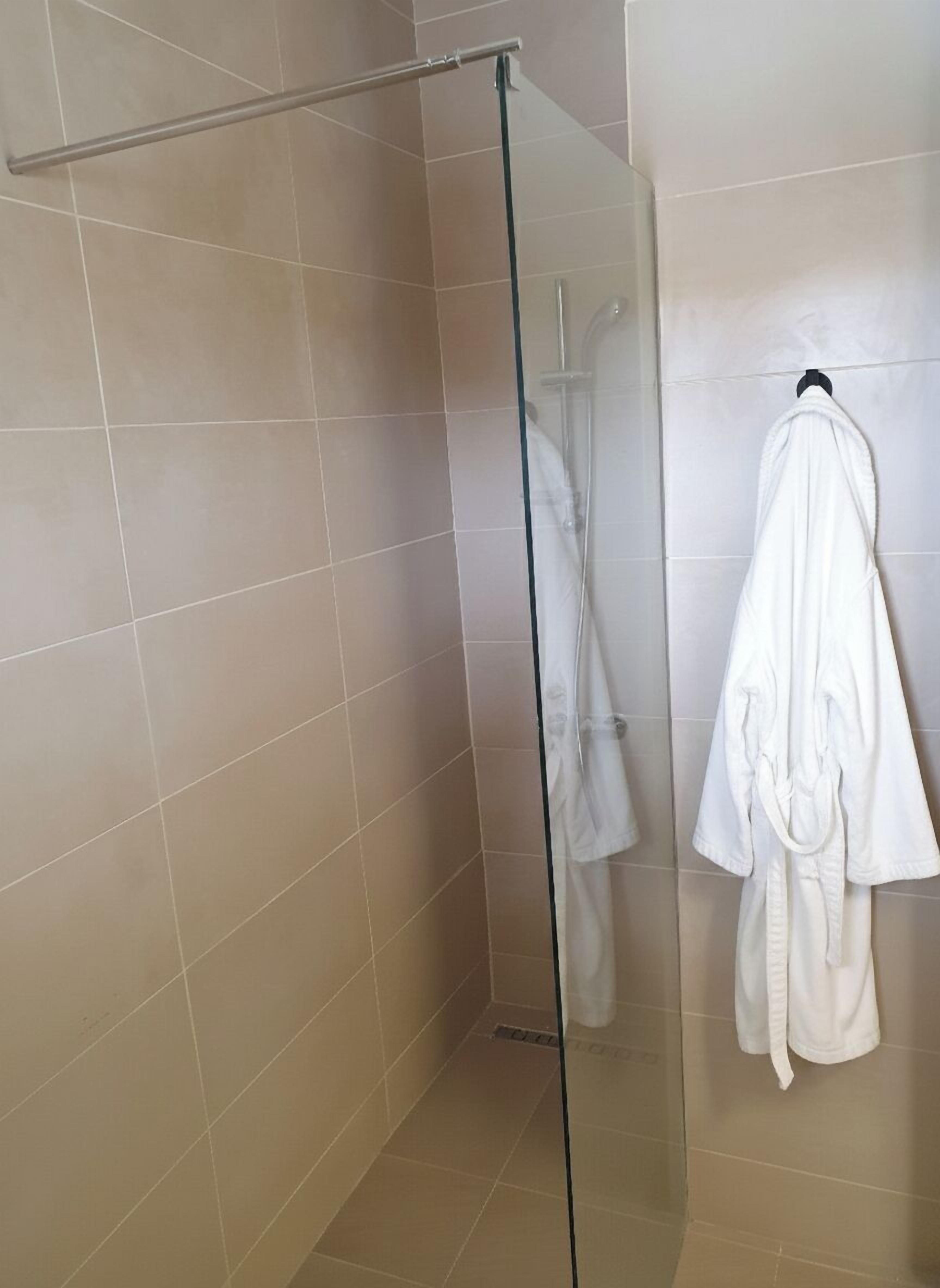 A glass-enclosed shower area with a towel rack holding a white robe.