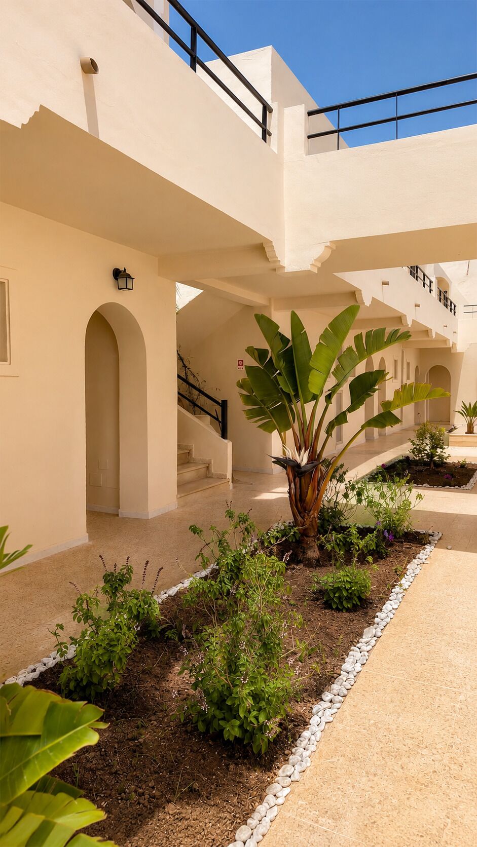 A building with multiple levels, outdoor staircases, and a garden area with various plants.