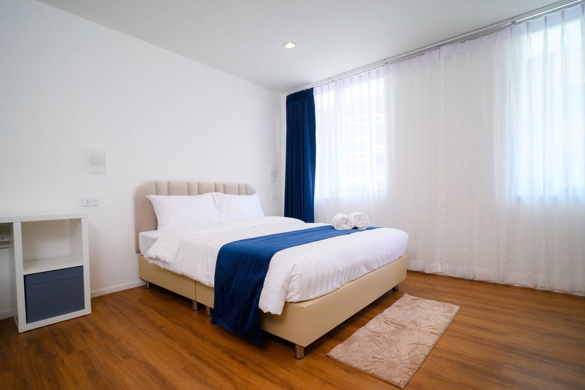 A neatly arranged bedroom with a bed, a bedside table, and a desk.
