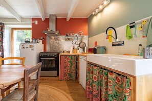 Une cuisine avec une table en bois, des chaises, une cuisinière et un réfrigérateur.