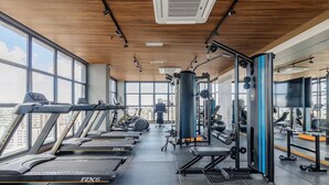 Un gimnasio con cintas de correr, máquinas de pesas y una pared de espejos.
