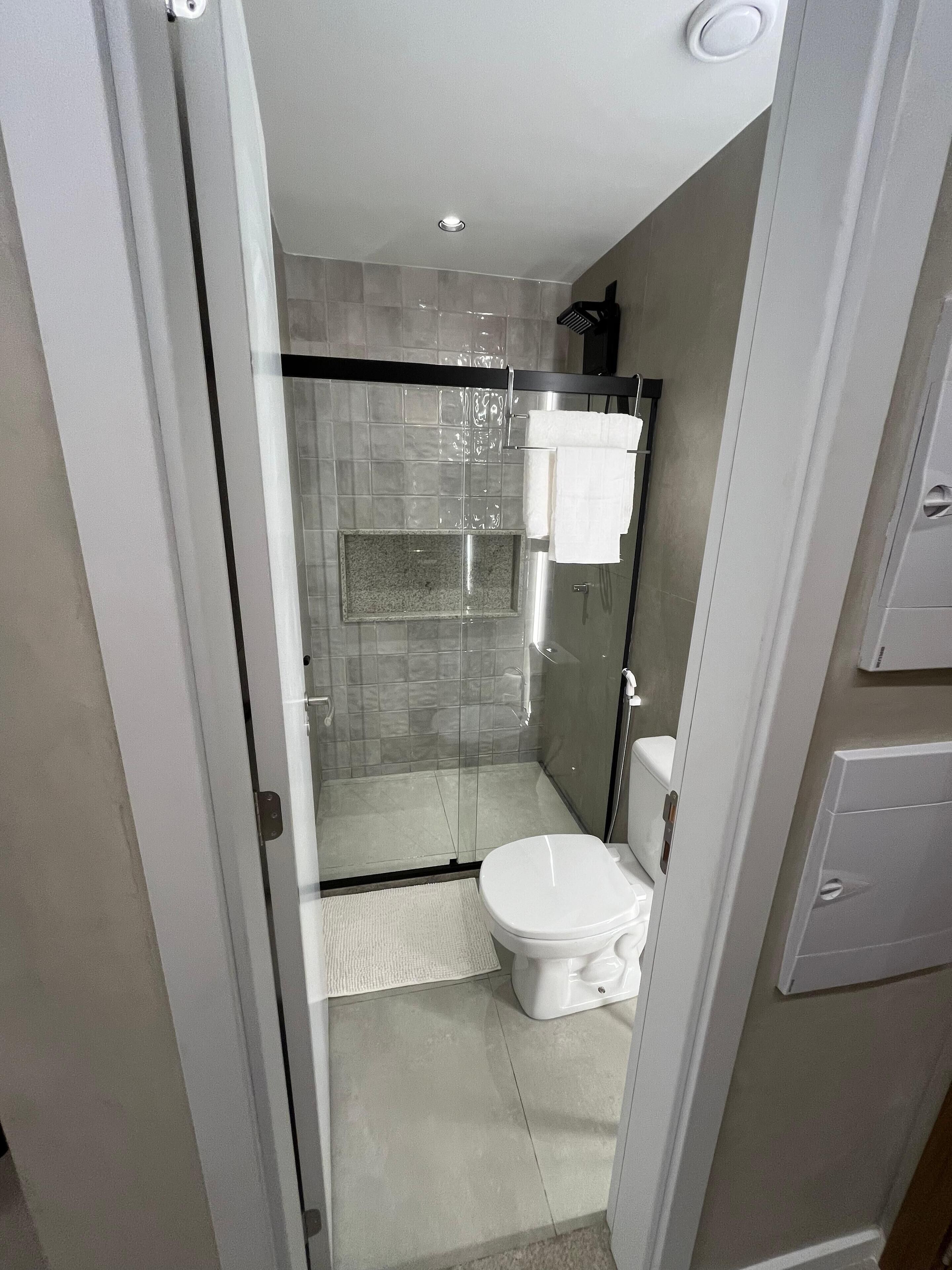 Un bagno moderno con cabina doccia in vetro, un water e un porta asciugamani.