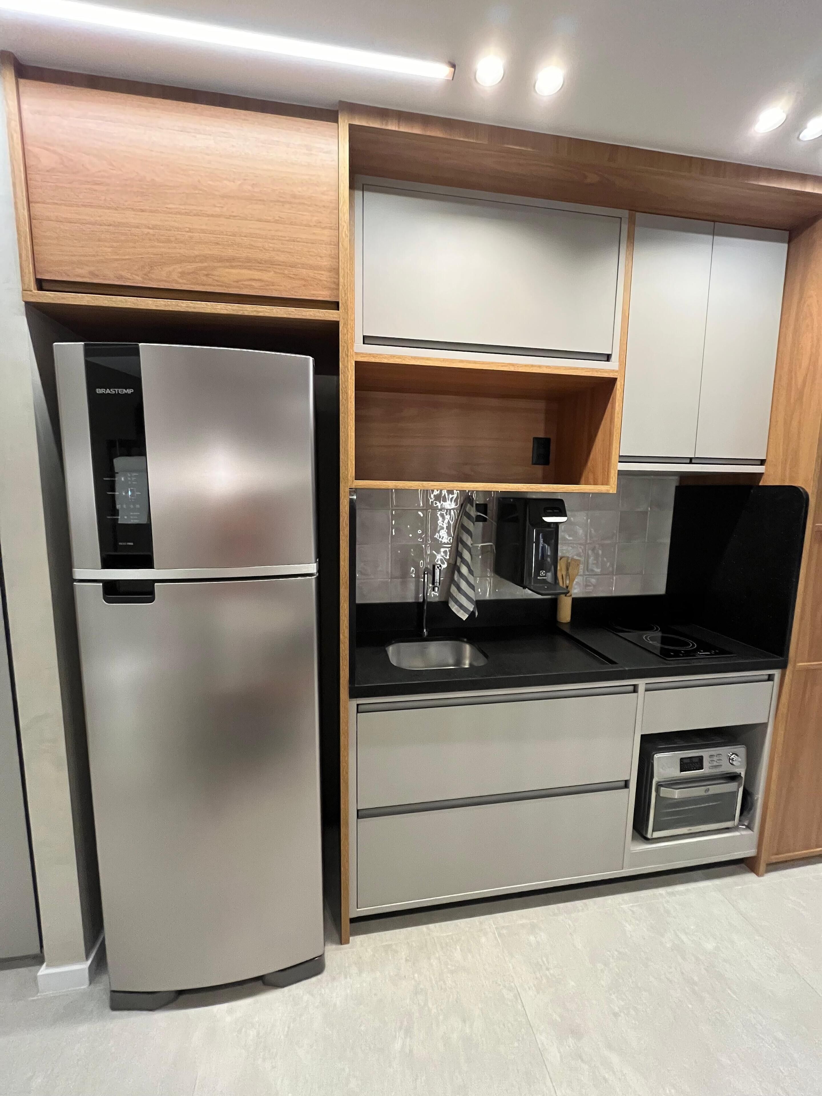 Eine moderne Küche mit einem Edelstahl-Kühlschrank, einem Einbauofen und Holzschränken.