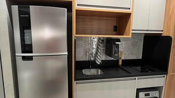 Eine moderne Küche mit einem Edelstahl-Kühlschrank, einem Einbauofen und Holzschränken.