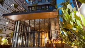 Un hotel moderno con entrada de vidrio, diseño vertical y el número '188' en la fachada.