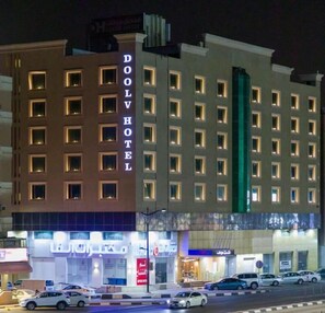 A multi-story hotel with illuminated signage, a ground-level retail area, and a parking lot. - Doolve Al Khobar (Al Khobar)