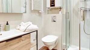 A modern bathroom with a glass-enclosed shower, a white sink with a wooden vanity, and a toilet. - Cozy Stay for 4 in the Heart (Paris)
