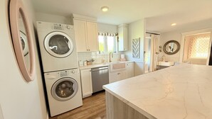A modern kitchen with built-in appliances, a marble countertop, and wooden flooring.