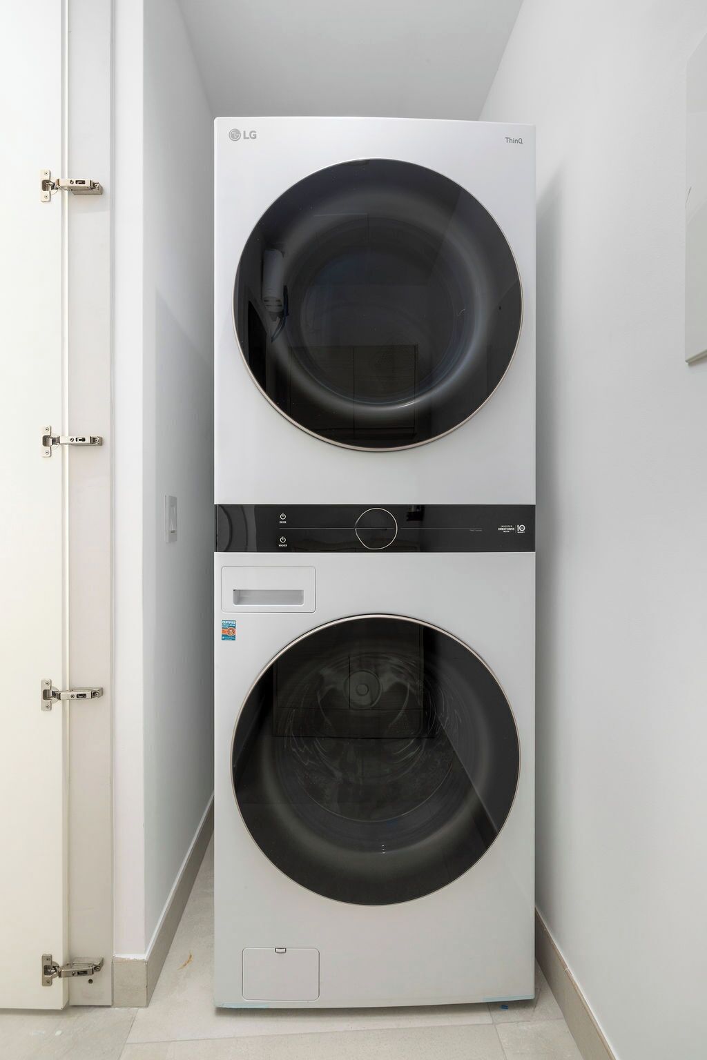 Een gestapelde wasmachine en droger in een smalle gang.