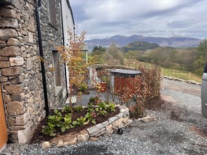 A stone building with a garden area, including plants and a small shed.