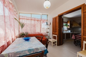 A dining area with a table, chairs, a sofa, and a kitchen in the background. - Villa 'Giacrì - Rilievo' with Private Terrace, Wi-Fi, and Air Conditioning (Rilievo)