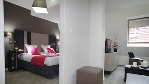 A modern hotel room with a bed, bedside table, lamp, and a small seating area with a table and chair. - T2 charmant en centre-ville, près des commerces (Strasbourg)