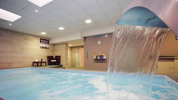 A swimming pool with a water feature, a clock on the wall, and a sign with emergency instructions. - T2 charmant en centre-ville, près des commerces (Strasbourg)