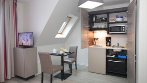 A compact kitchen with a dining area, a TV, and a built-in oven. - T2 charmant en centre-ville, près des commerces (Strasbourg)