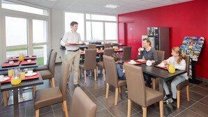 A dining area with tables, chairs, and a serving staff member. - Chambre twin confortable à 10 min du centre ville (Orleans)