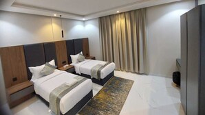 A modern hotel room with two beds, a large mirror, a flat-screen TV, and a large window with curtains.