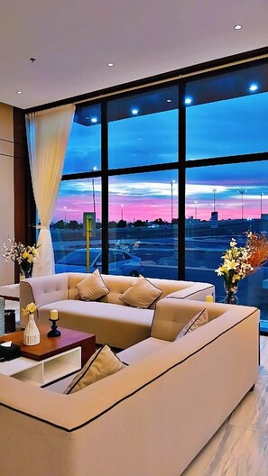 A modern living room with a large window, a sofa, a side table, and a vase with flowers.