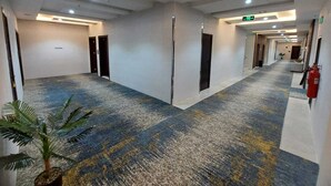 A hotel corridor with a patterned carpet, doors, and a fire extinguisher.