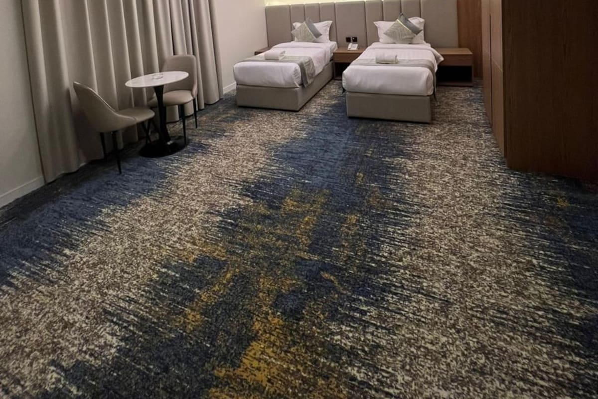 Une chambre d’hôtel avec deux lits, une petite table et une chaise.