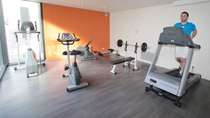 Un gimnasio con cintas de correr, una bicicleta estática y un banco de pesas.