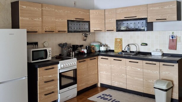Une cuisine moderne avec des meubles en bois, un four à micro-ondes, une cuisinière et un ventilateur de plafond.