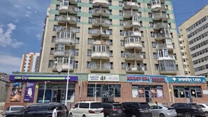 Un immeuble à plusieurs étages doté de balcons, un parking à l’avant et divers commerces, notamment un spa et une banque.