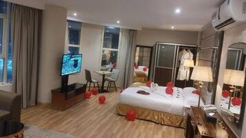 Una habitación de hotel con cama, escritorio, televisor y armario.