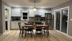 A modern kitchen with white cabinets, a wooden dining table, and black chairs.