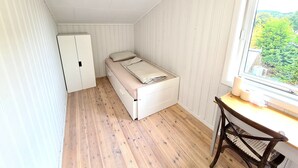 En lille lejlighed med et værelse, seng, skrivebord og garderobeskab.