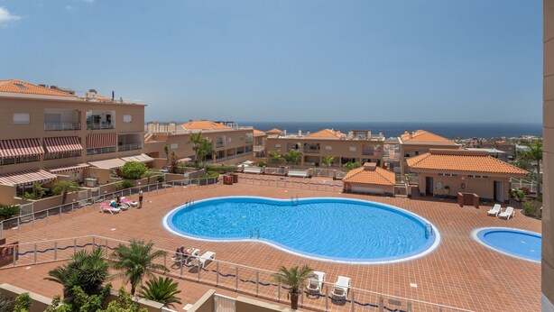 A rooftop swimming pool with lounge chairs, surrounded by buildings with terracotta roofs and a clear view of the sea. - Brisas de Chasna Holiday Apartment with Sea Views, Shared Pool and Wi-Fi (Costa Adeje)