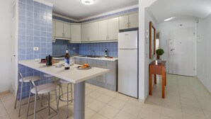 A modern kitchen with white cabinets, blue tiles, a white countertop, and a bar stool. - Brisas de Chasna Holiday Apartment with Sea Views, Shared Pool and Wi-Fi (Costa Adeje)
