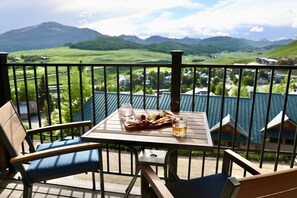 Ein Balkon mit Esstisch, der auf eine gebirgige Landschaft blickt.