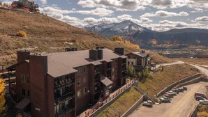 A multi-story building with a modern design, located on a hillside with a view of a mountain range. - The Elk Mountain Escape (Mt. Crested Butte)