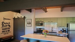 A modern kitchen with a central island, bar stools, a microwave, oven, and refrigerator. - The Elk Mountain Escape (Mt. Crested Butte)