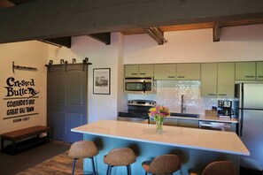 A modern kitchen with a central island, bar stools, a microwave, oven, and refrigerator. - The Elk Mountain Escape (Mt. Crested Butte)