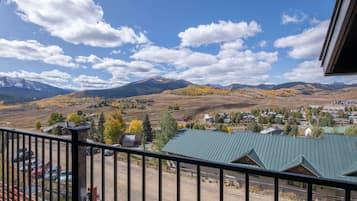 A balcony with a view of a mountain range and a small town below.