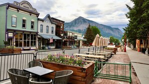 A restaurant patio with outdoor seating and a mountain backdrop. - The Elk Mountain Escape (Mt. Crested Butte)