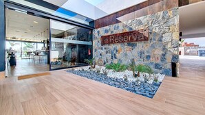 A modern building with a 'Reserve' sign, glass doors, and a stone wall with a fire extinguisher.