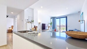 A modern kitchen with a central island, a dining area with a large woven bowl, and a view of the city through large windows.