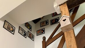 Una escalera de madera con barandilla y un muro decorado con marcos.
