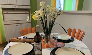 Ein Esstisch mit Tellern, Besteck, einer Weinflasche und einer Blumenvase.
