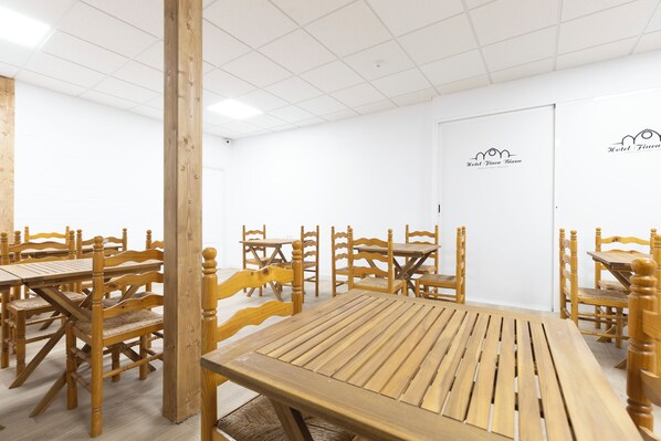 A room with wooden tables and chairs, a white ceiling, and a door with a logo. - Hotel Finca Biazu (Ocaña)