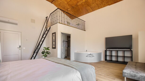 Un dormitorio con una cama, un banco, una bañera y un televisor.