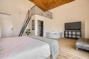 A bedroom with a bed, a bench, a bathtub, and a TV. - Hotel Finca Biazu (Ocaña)